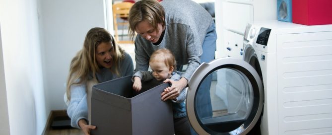 A fiatal család a mosógépbe pakolja a ruhákat