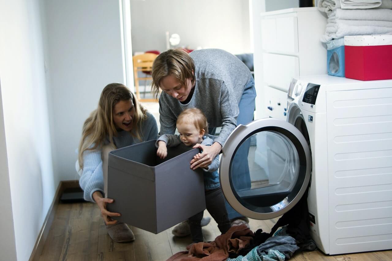 A fiatal család a mosógépbe pakolja a ruhákat